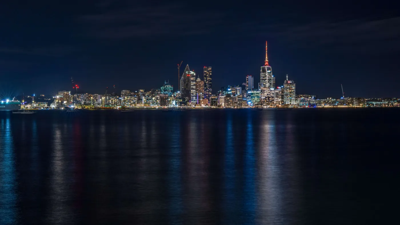 Auckland skyline at night, lights reflected on the harbour